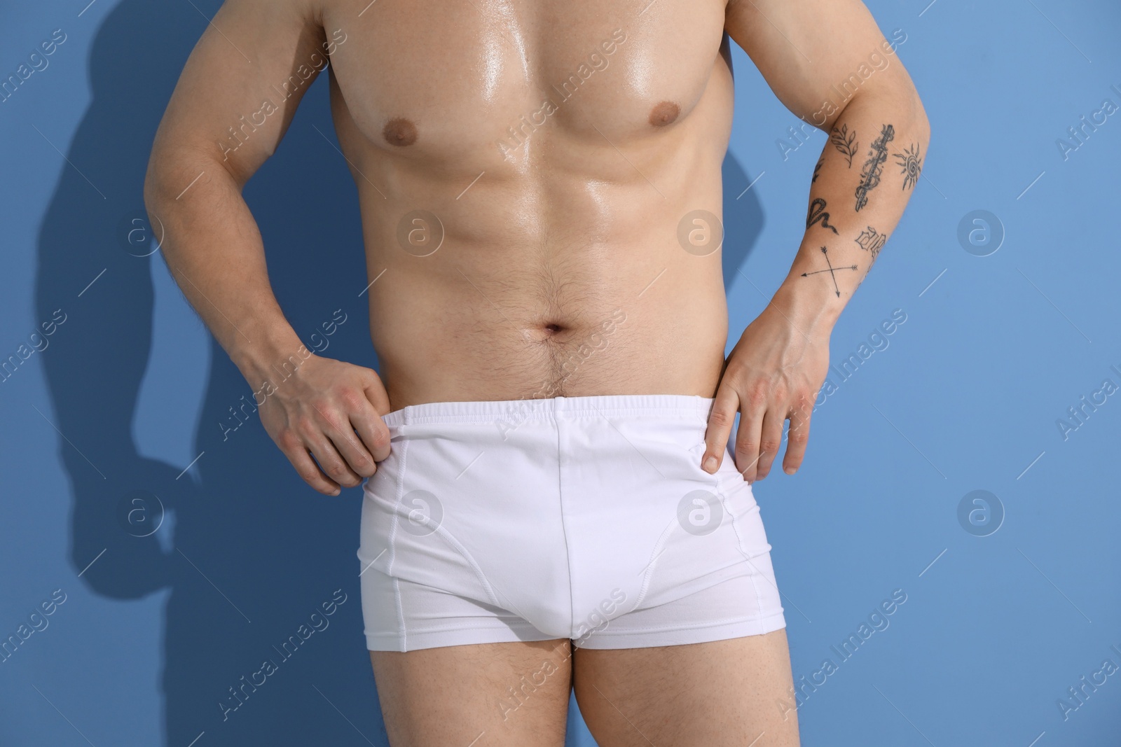 Young man in stylish white underwear on light blue background, closeup Photo of Young man in stylish white underwear on light blue background, closeup