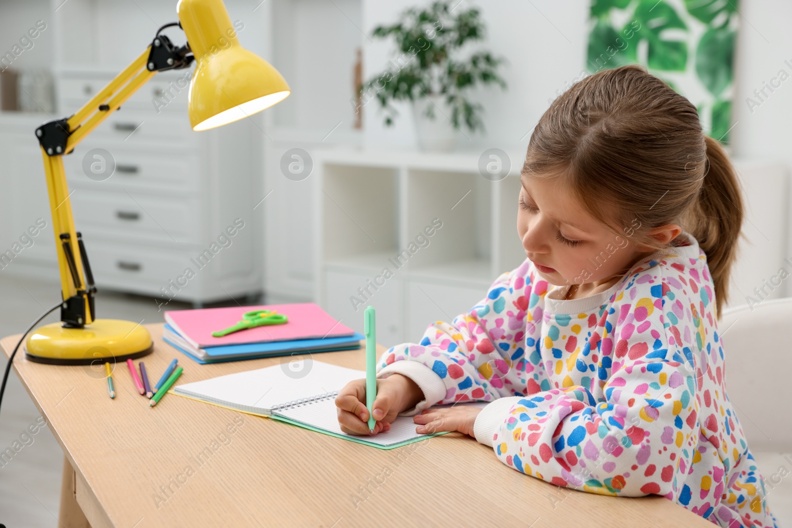 Little girl doing homework at table indoors Photo of Little girl doing homework at table indoors