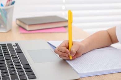 Photo of Little girl doing homework at table indoors, closeup