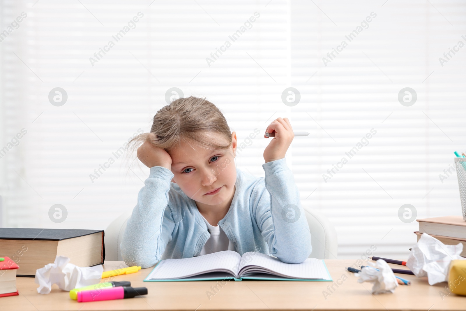 Tired little girl doing homework at table indoors Photo of Tired little girl doing homework at table indoors