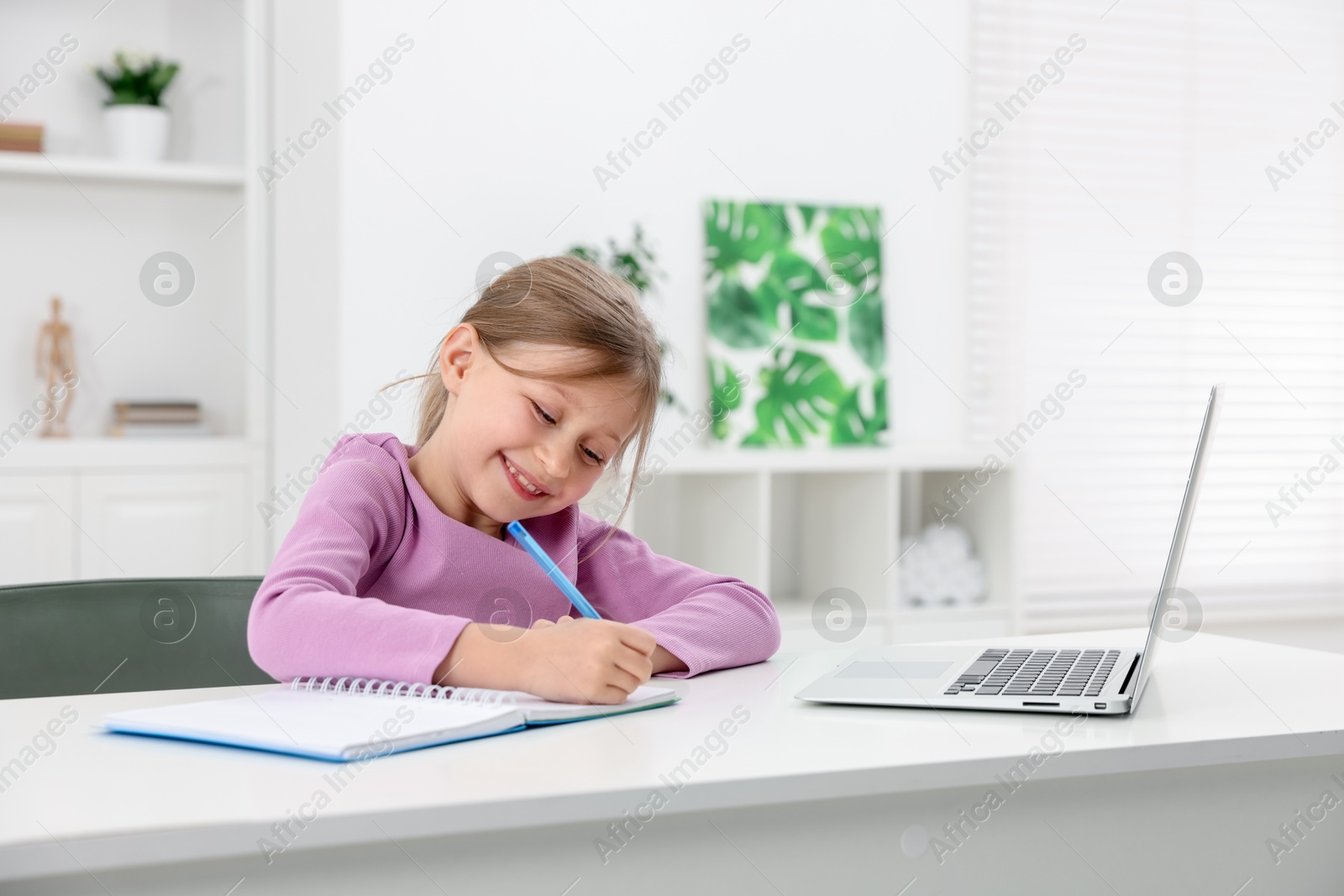 Little girl doing homework at table indoors Photo of Little girl doing homework at table indoors