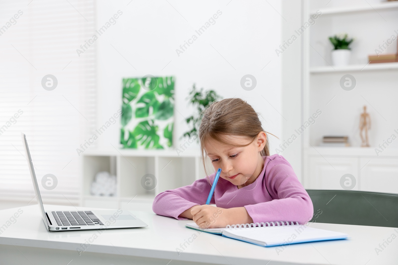 Little girl doing homework at table indoors Photo of Little girl doing homework at table indoors