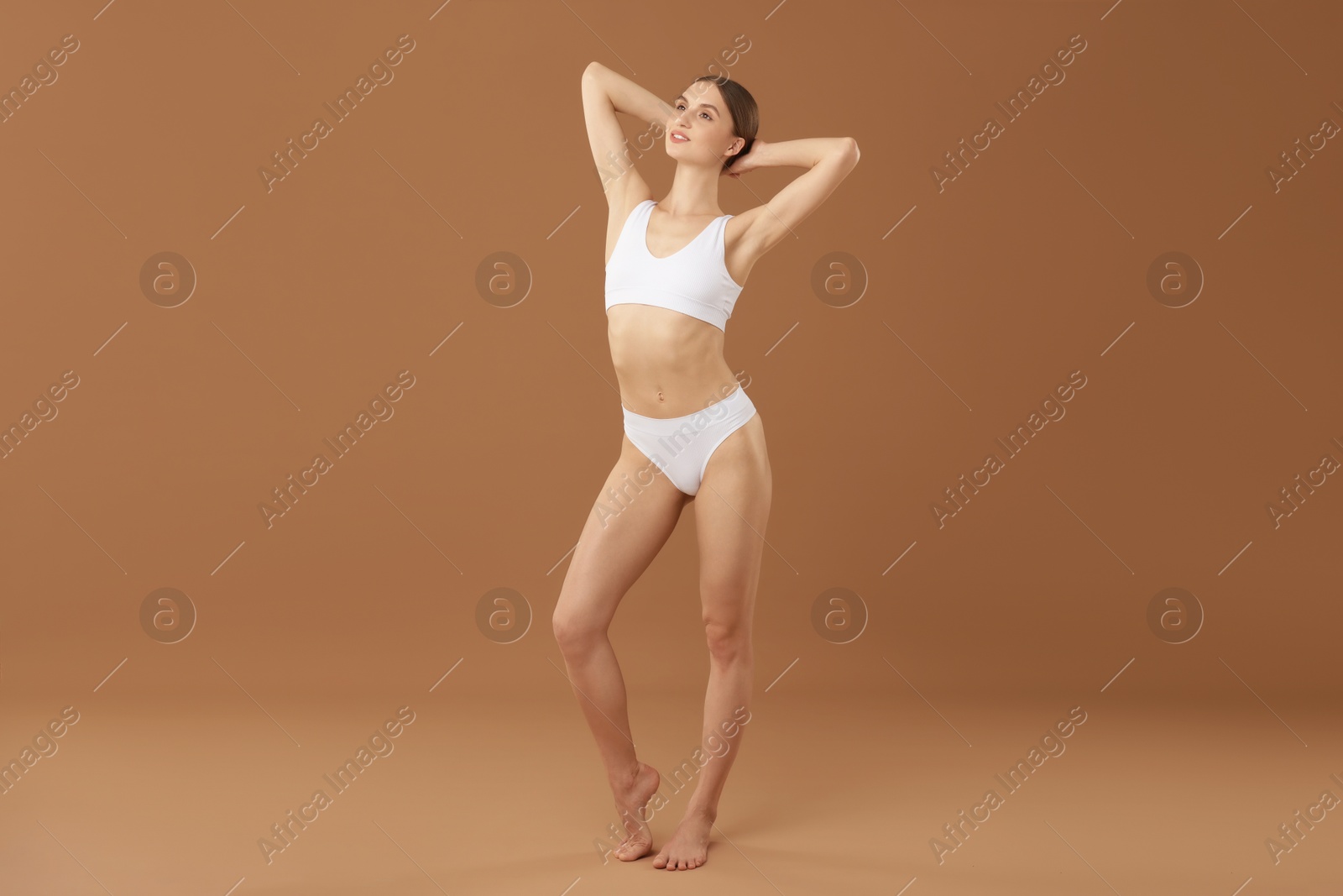 Beautiful woman with perfect slim body on beige background Photo of Beautiful woman with perfect slim body on beige background