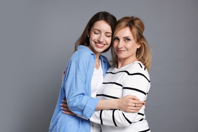 Photo of Mother and daughter hugging on grey background