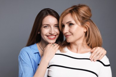 Photo of Mother and daughter hugging on grey background