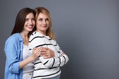 Photo of Mother and daughter hugging on grey background. Space for text