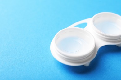 Photo of Contact lenses in case on light blue background, closeup. Space for text