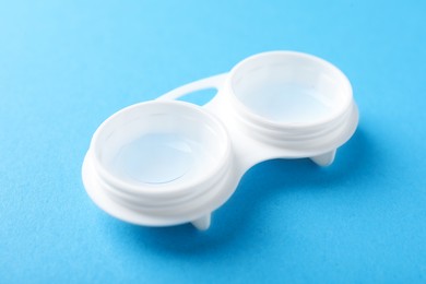 Photo of Contact lenses in case on light blue background, closeup
