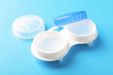Photo of Contact lenses in case on light blue background, closeup