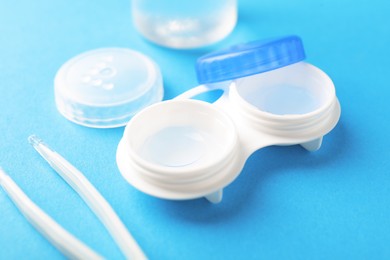 Photo of Contact lenses in case and tweezers on light blue background, closeup