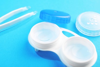Photo of Contact lenses in case and tweezers on light blue background, closeup