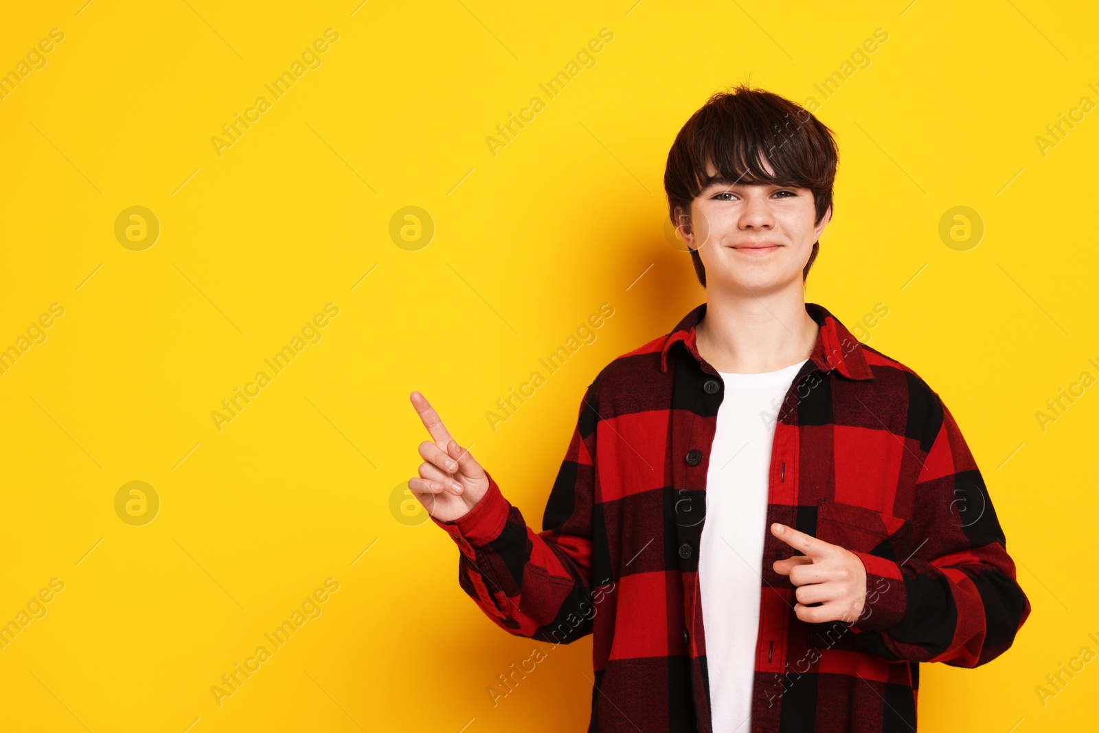 Portrait of teenage boy on orange background, space for text Photo of Portrait of teenage boy on orange background, space for text