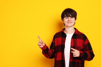 Photo of Portrait of teenage boy on orange background, space for text