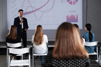 Photo of Male business trainer giving lecture in conference room with projection screen