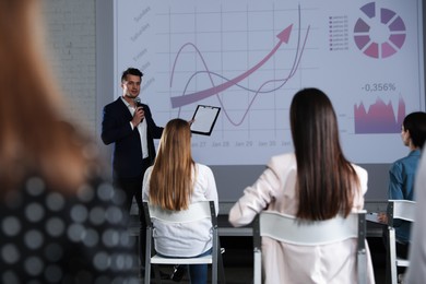 Photo of Male business trainer giving lecture in conference room with projection screen