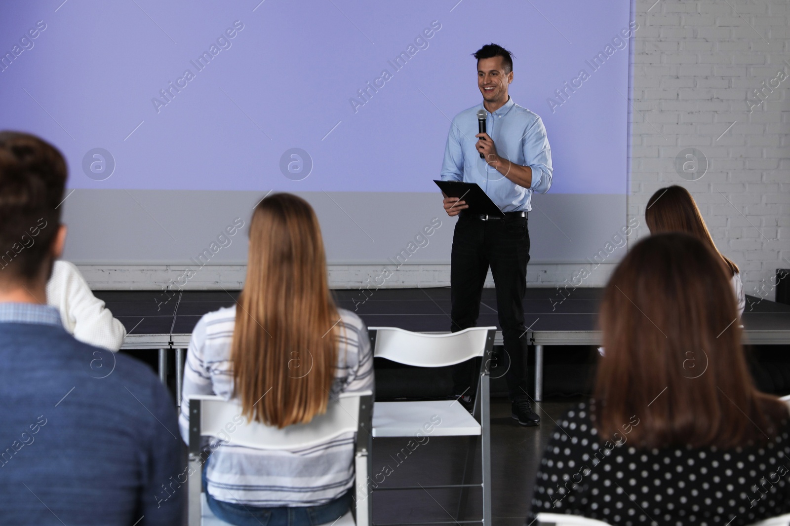 Male business trainer giving lecture in conference room with projection screen Photo of Male business trainer giving lecture in conference room with projection screen