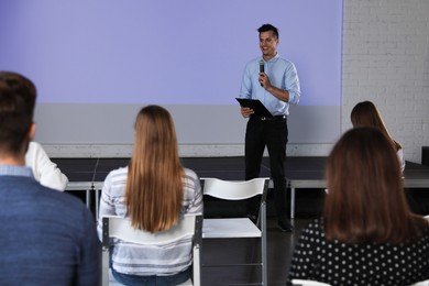 Photo of Male business trainer giving lecture in conference room with projection screen