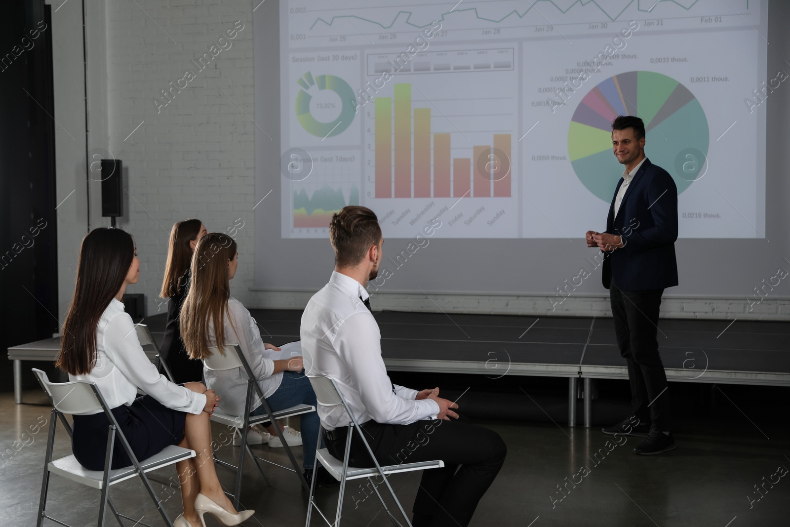 Male business trainer giving lecture in conference room with projection screen Photo of Male business trainer giving lecture in conference room with projection screen