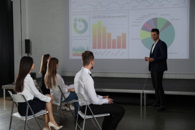 Photo of Male business trainer giving lecture in conference room with projection screen