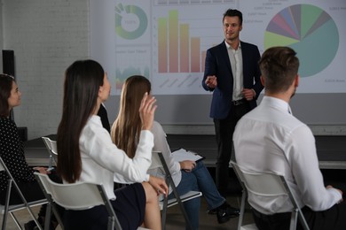 Photo of Male business trainer giving lecture in conference room with projection screen