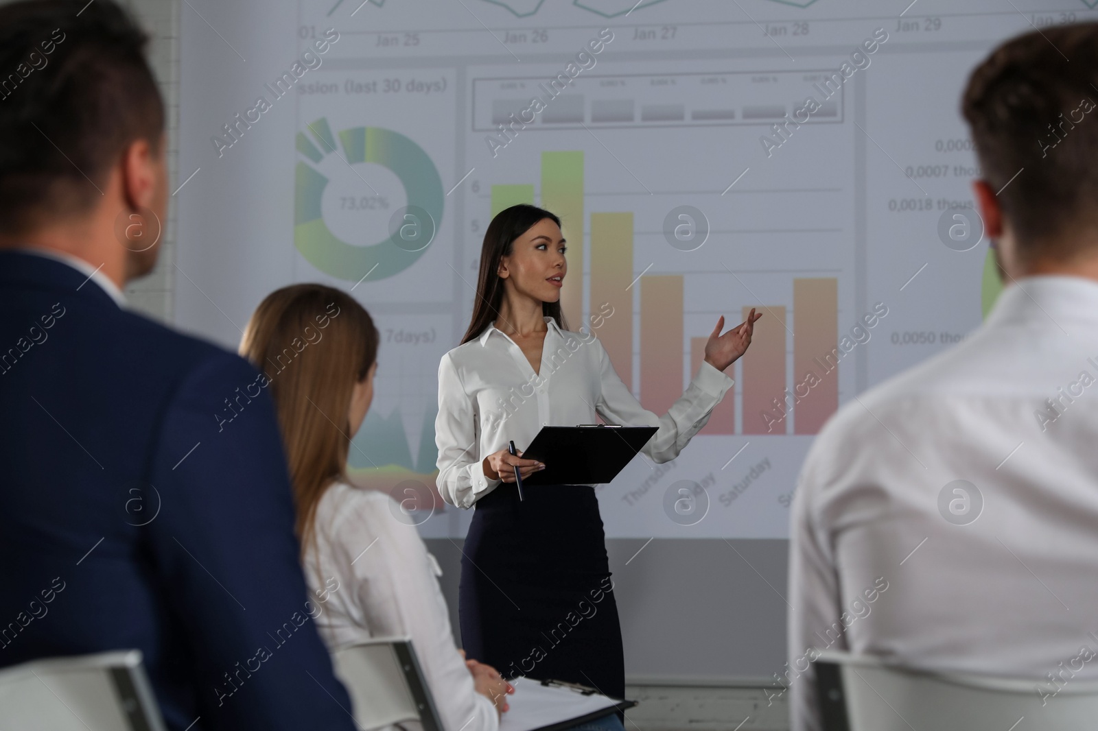 Female business trainer giving lecture in conference room with projection screen Photo of Female business trainer giving lecture in conference room with projection screen