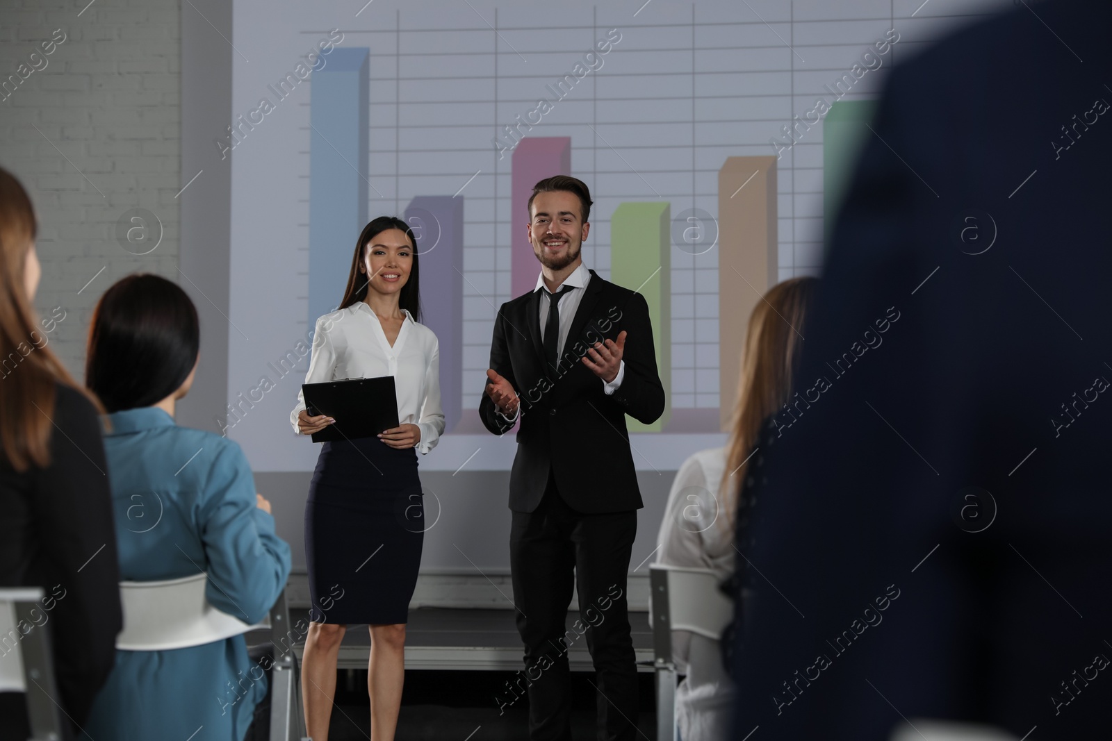 Business trainers giving lecture in conference room with projection screen Photo of Business trainers giving lecture in conference room with projection screen
