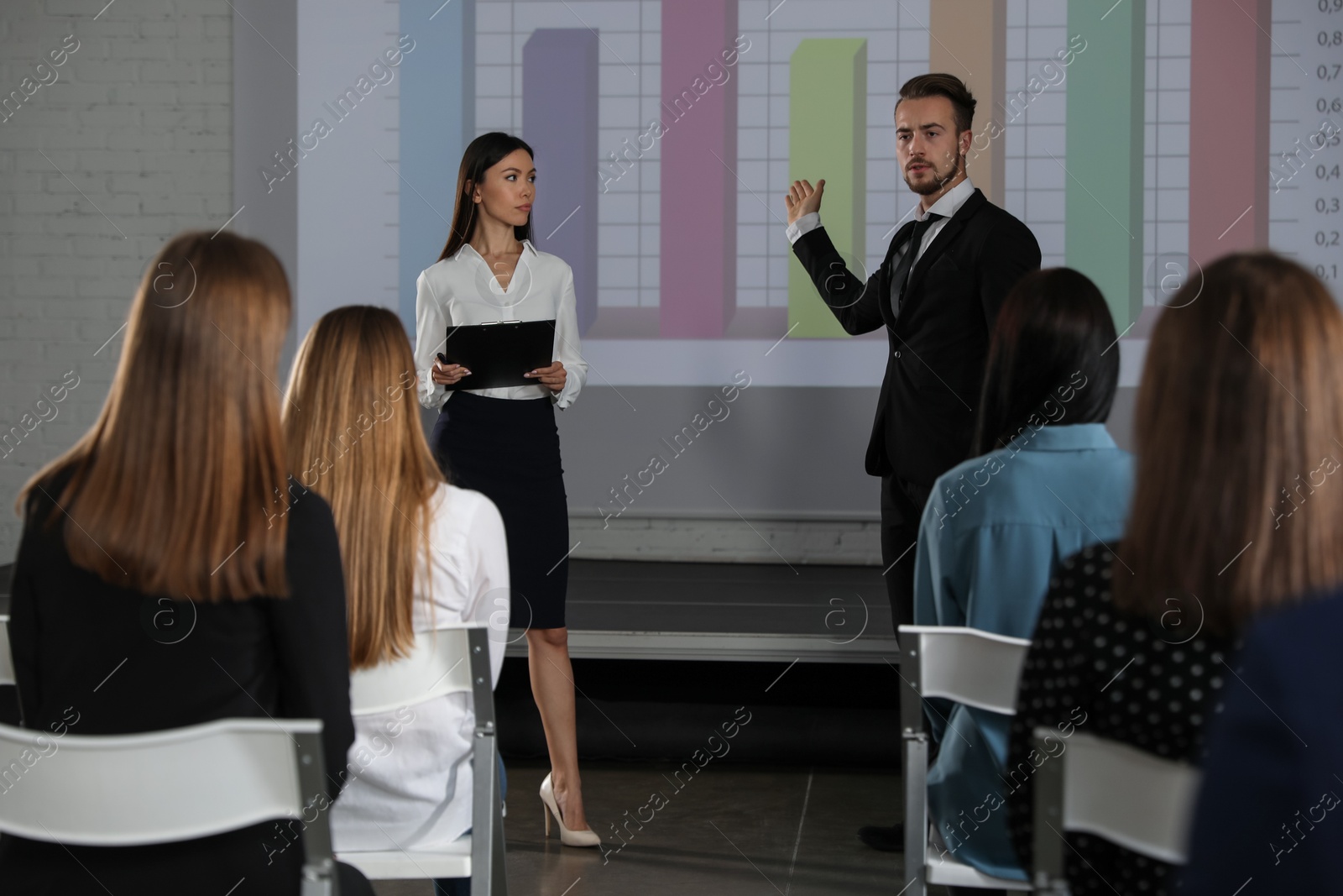 Business trainers giving lecture in conference room with projection screen Photo of Business trainers giving lecture in conference room with projection screen
