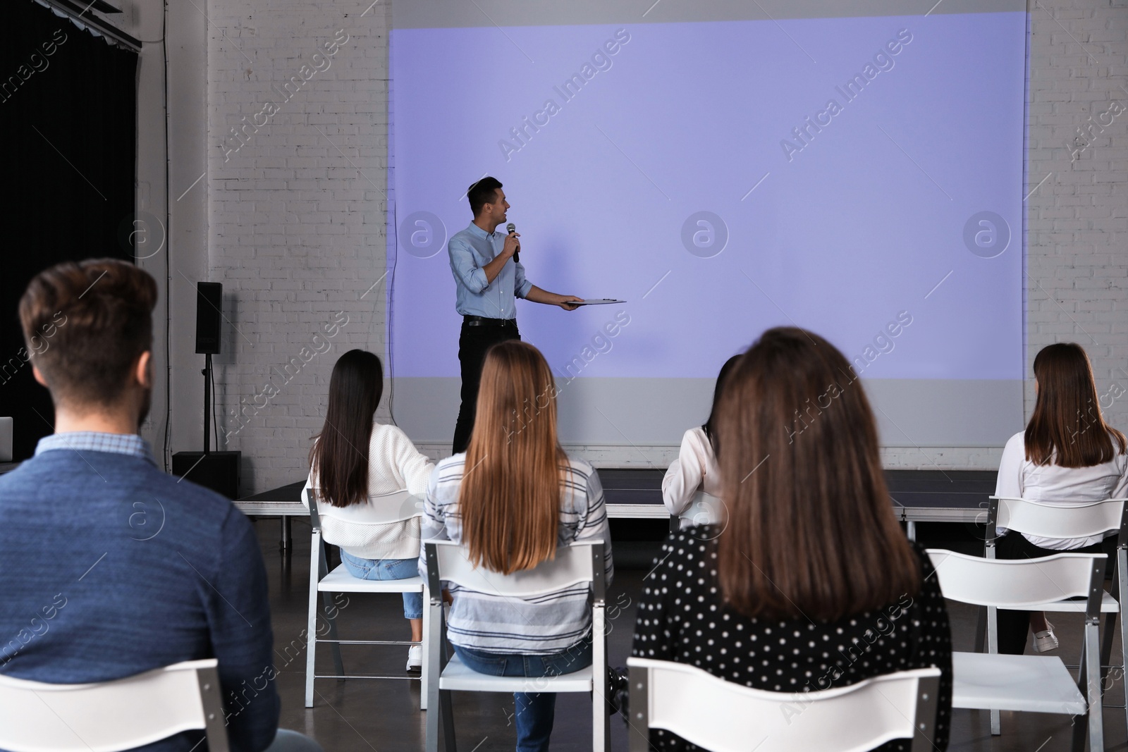 Male business trainer giving lecture in conference room with projection screen Photo of Male business trainer giving lecture in conference room with projection screen