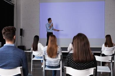 Photo of Male business trainer giving lecture in conference room with projection screen