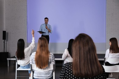 Photo of Male business trainer giving lecture in conference room with projection screen