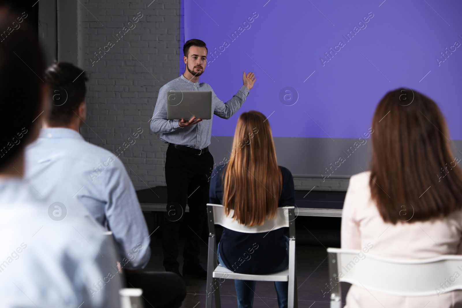 Male business trainer with laptop giving lecture in conference room with projection screen Photo of Male business trainer with laptop giving lecture in conference room with projection screen