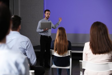 Photo of Male business trainer with laptop giving lecture in conference room with projection screen