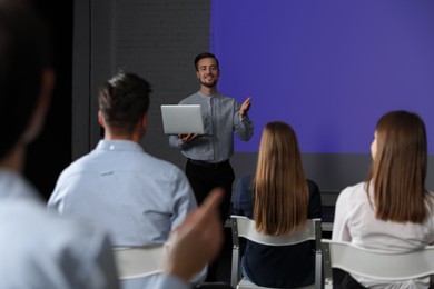 Photo of Male business trainer with laptop giving lecture in conference room with projection screen
