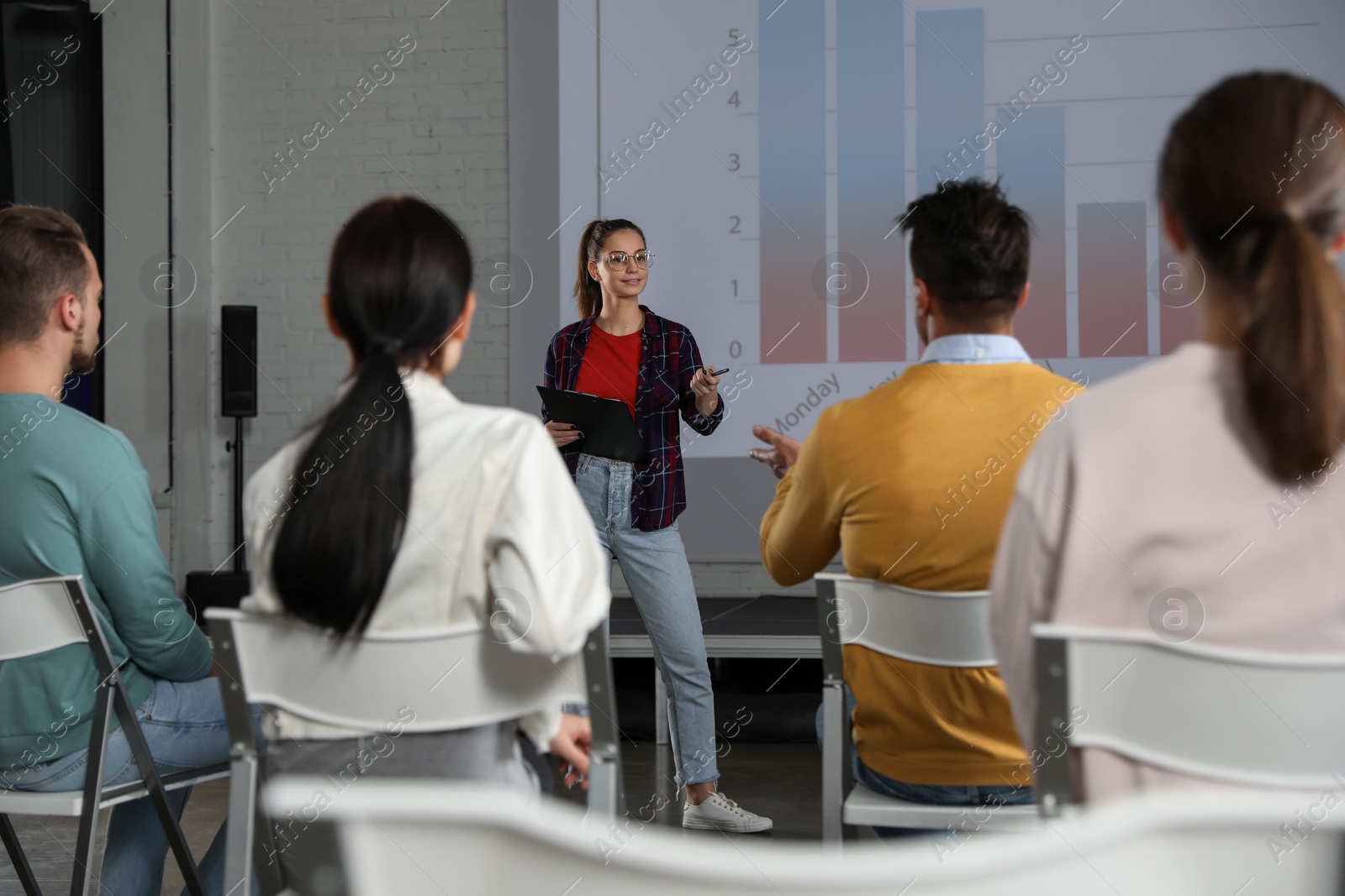 Female business trainer giving lecture in conference room with projection screen Photo of Female business trainer giving lecture in conference room with projection screen