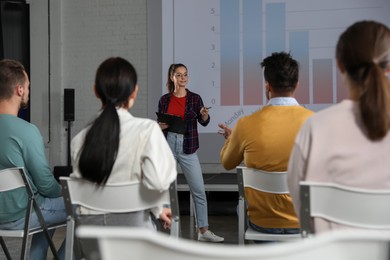 Photo of Female business trainer giving lecture in conference room with projection screen