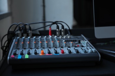 Photo of Modern audio mixing console on black table indoors, closeup. Music equipment