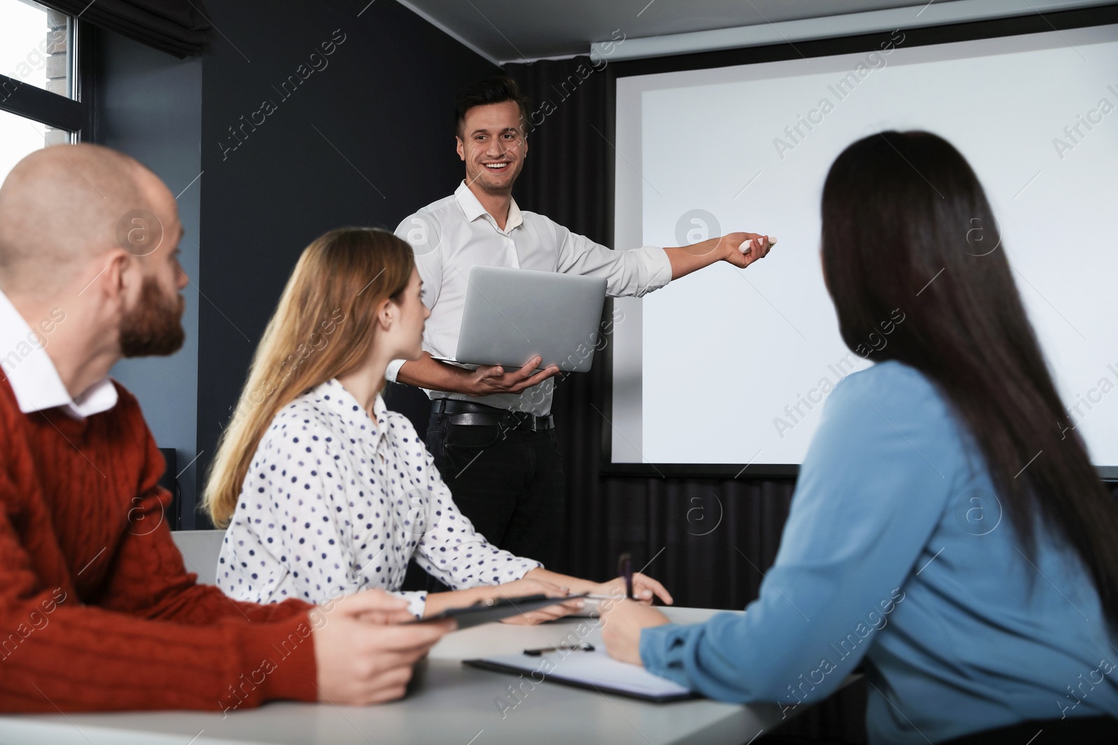 Business people listening to speaker in conference room with video projection screen Photo of Business people listening to speaker in conference room with video projection screen