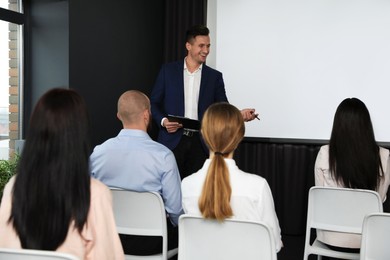 Photo of Business people at seminar in conference room with video projection screen