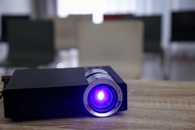 Photo of Modern video projector on wooden table in conference room