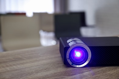 Photo of Modern video projector on wooden table in conference room. Space for text