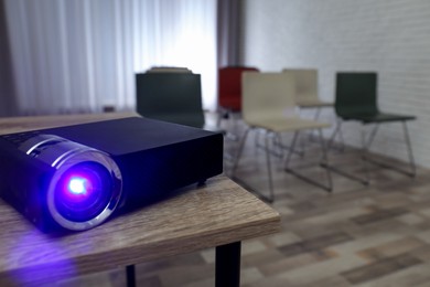 Photo of Modern video projector on wooden table in conference room