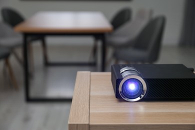 Photo of Modern video projector on wooden table in conference room. Space for text