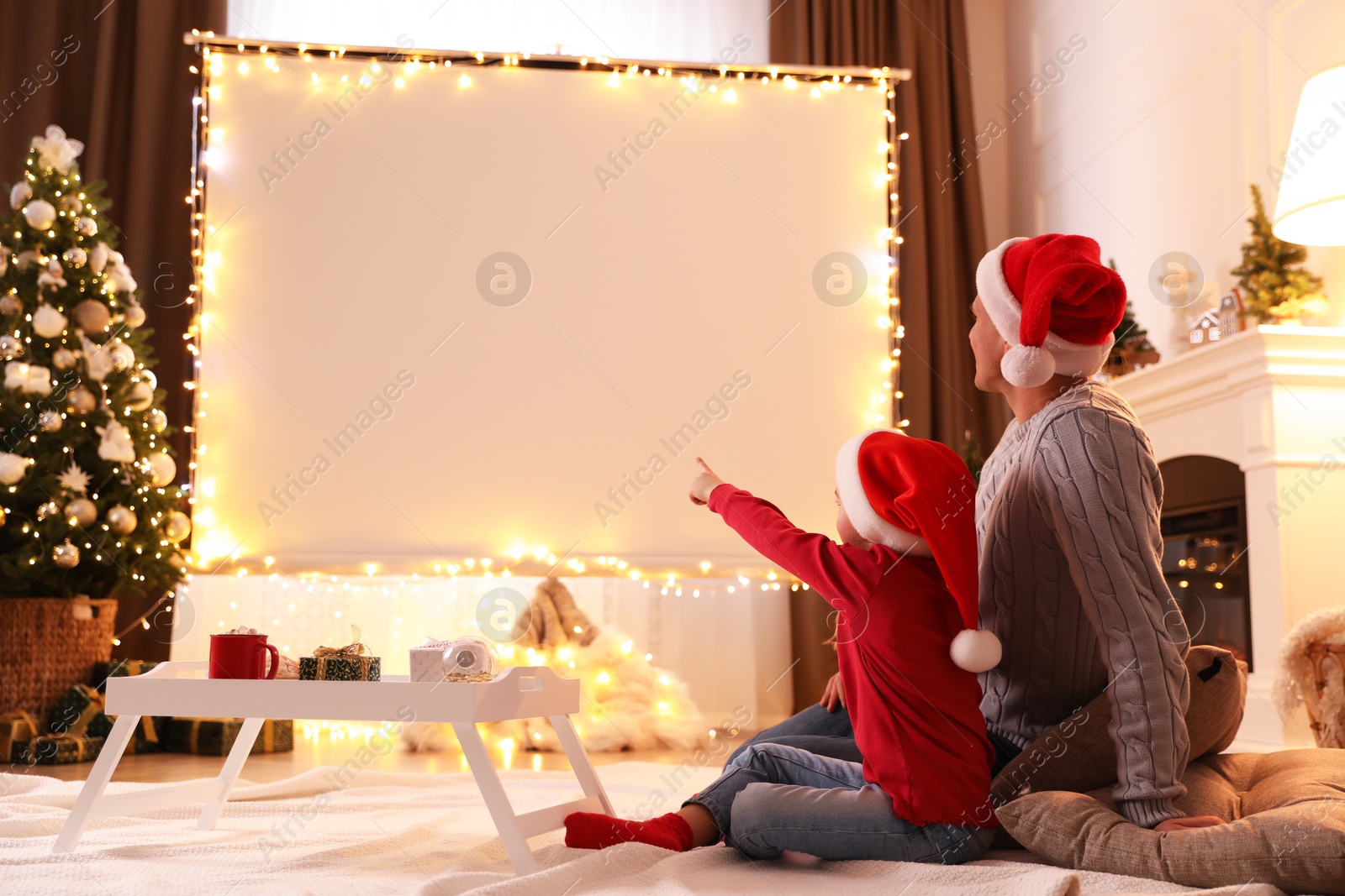 Father and daughter watching movie using video projector at home. Cozy Christmas atmosphere Photo of Father and daughter watching movie using video projector at home. Cozy Christmas atmosphere