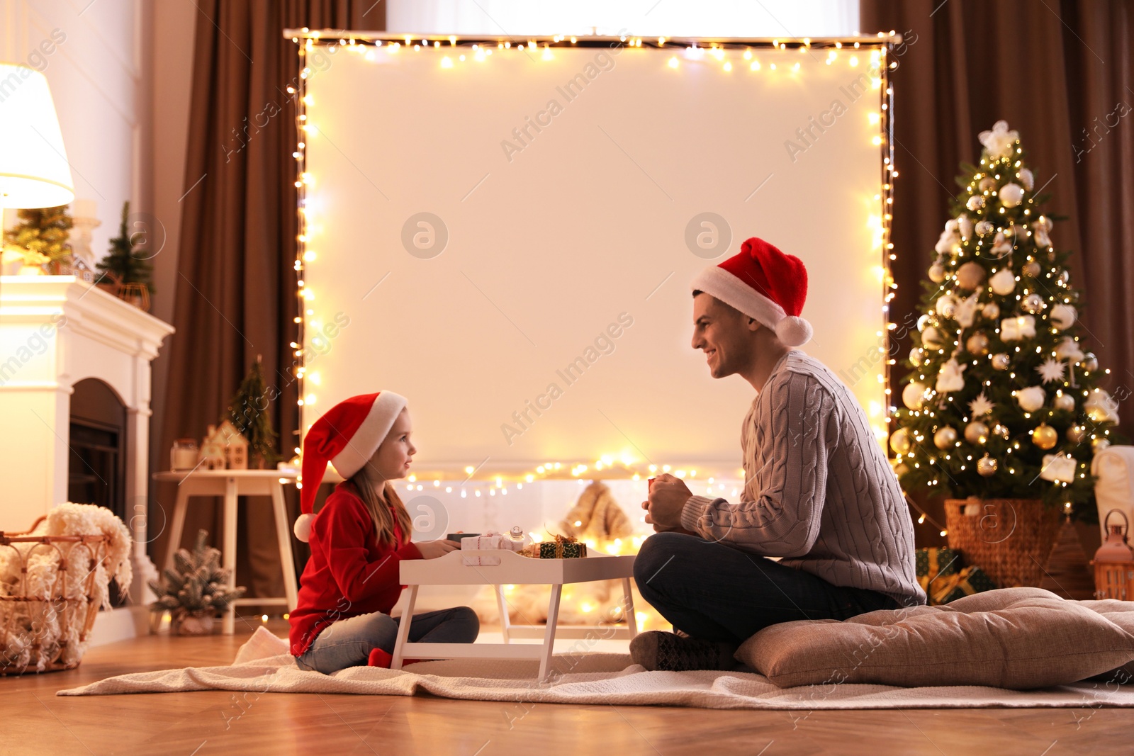 Father and daughter near video projector screen at home. Cozy Christmas atmosphere Photo of Father and daughter near video projector screen at home. Cozy Christmas atmosphere