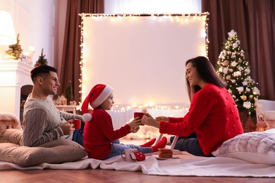 Photo of Family near video projector screen at home. Christmas time