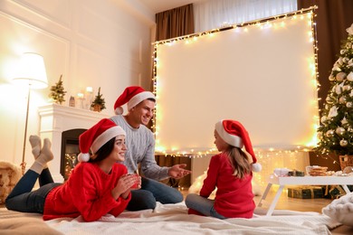 Photo of Family near video projector screen at home. Christmas time