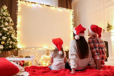 Photo of Family watching movie using video projector at home. Cozy Christmas atmosphere