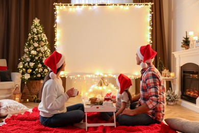 Photo of Family watching movie using video projector at home. Cozy Christmas atmosphere