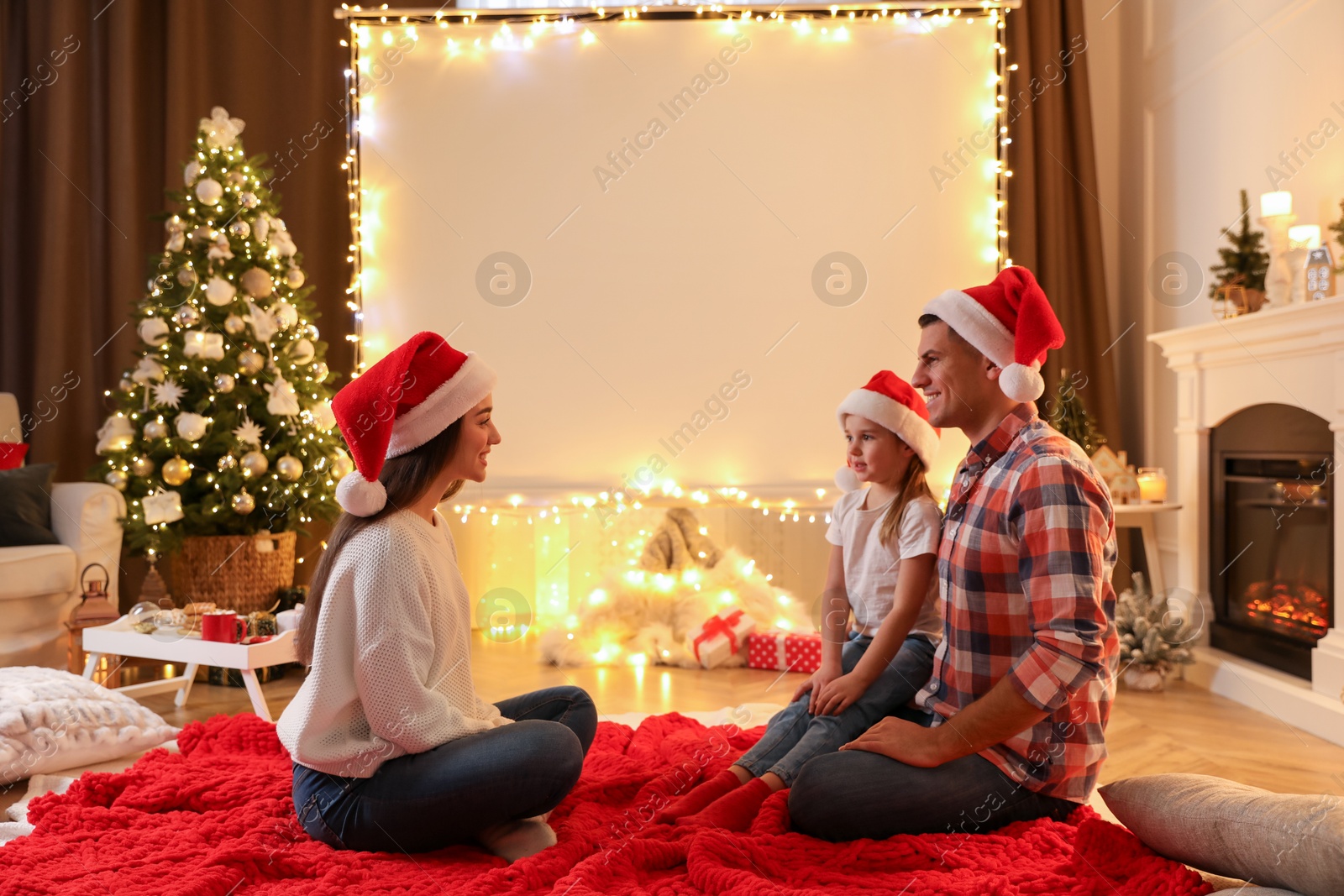Family near video projector screen at home. Cozy Christmas atmosphere Photo of Family near video projector screen at home. Cozy Christmas atmosphere