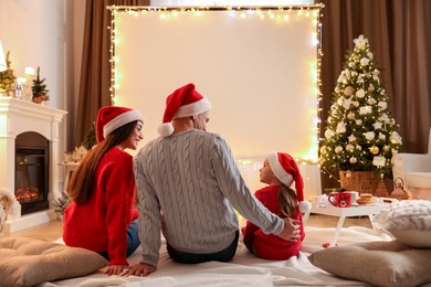 Photo of Family watching movie using video projector at home. Cozy Christmas atmosphere